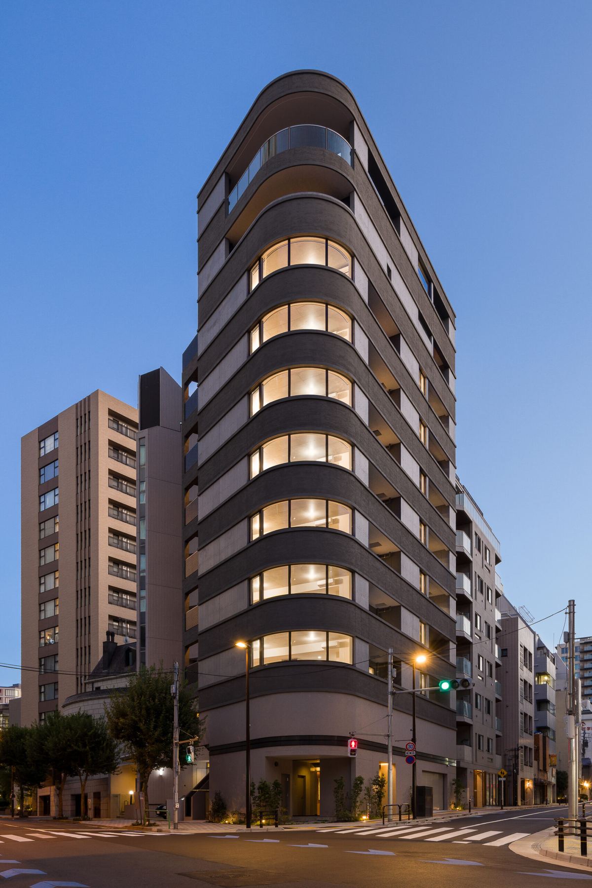 夕景の共同住宅。丸みのあるバルコニーが連なる外観